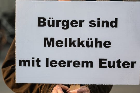 Ein Bürger demonstriert mit einem Plakat mit der Aufschrift "Bürger sind Melkkühe mit leerem Euter" gegen Abgabenlast.