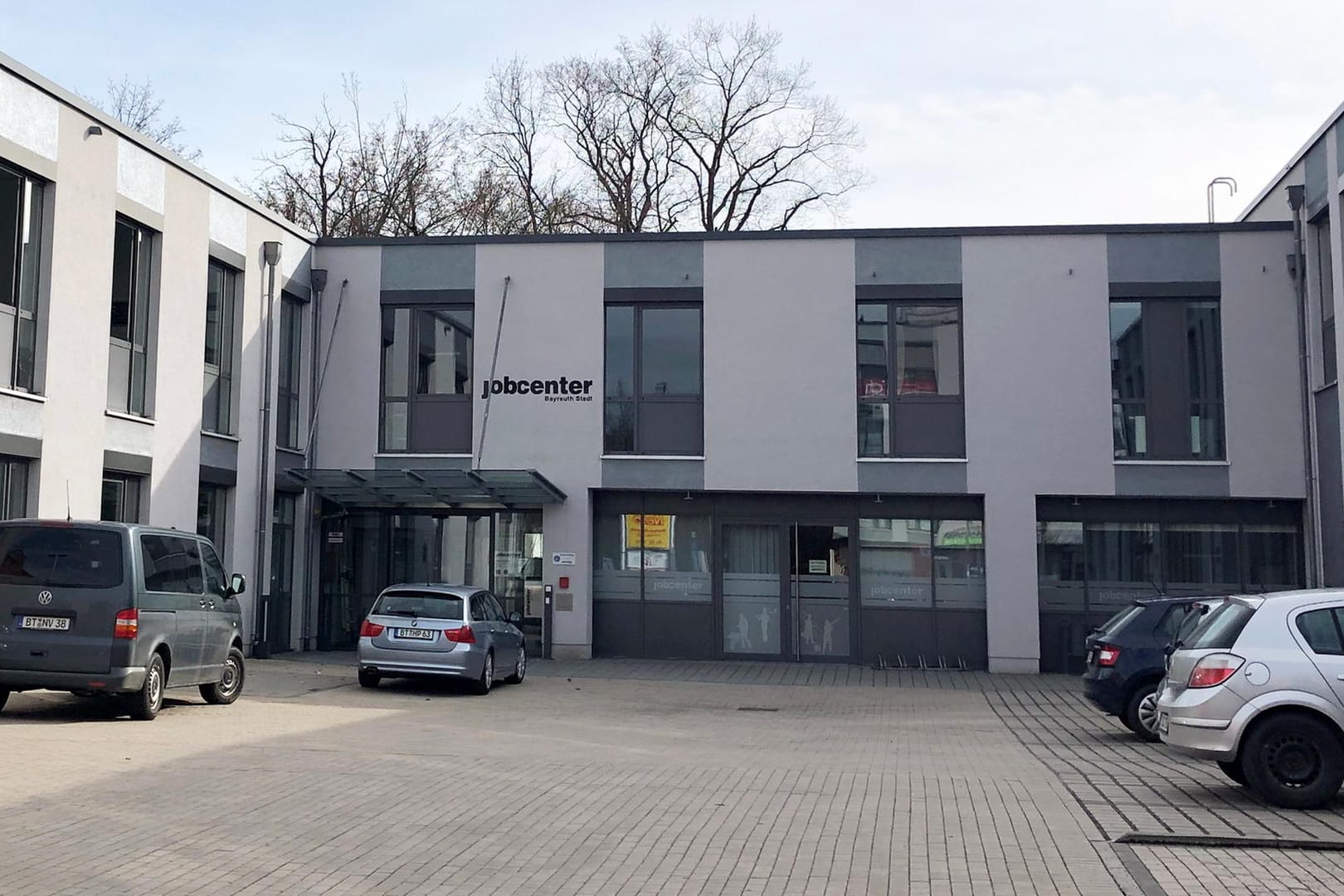 Jobcenter in Bayreuth: Zwei Zivilfahrzeuge der Polizei (li.) stehen vor dem Eingang des Gebäudes.