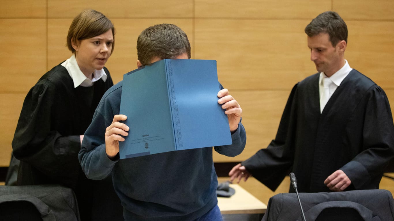Die eigenen Kollegen vergiftet: Der Angeklagte Klaus O. verdeckt im Gerichtssaal in Bielefeld sein Gesicht mit einer Aktenmappe.