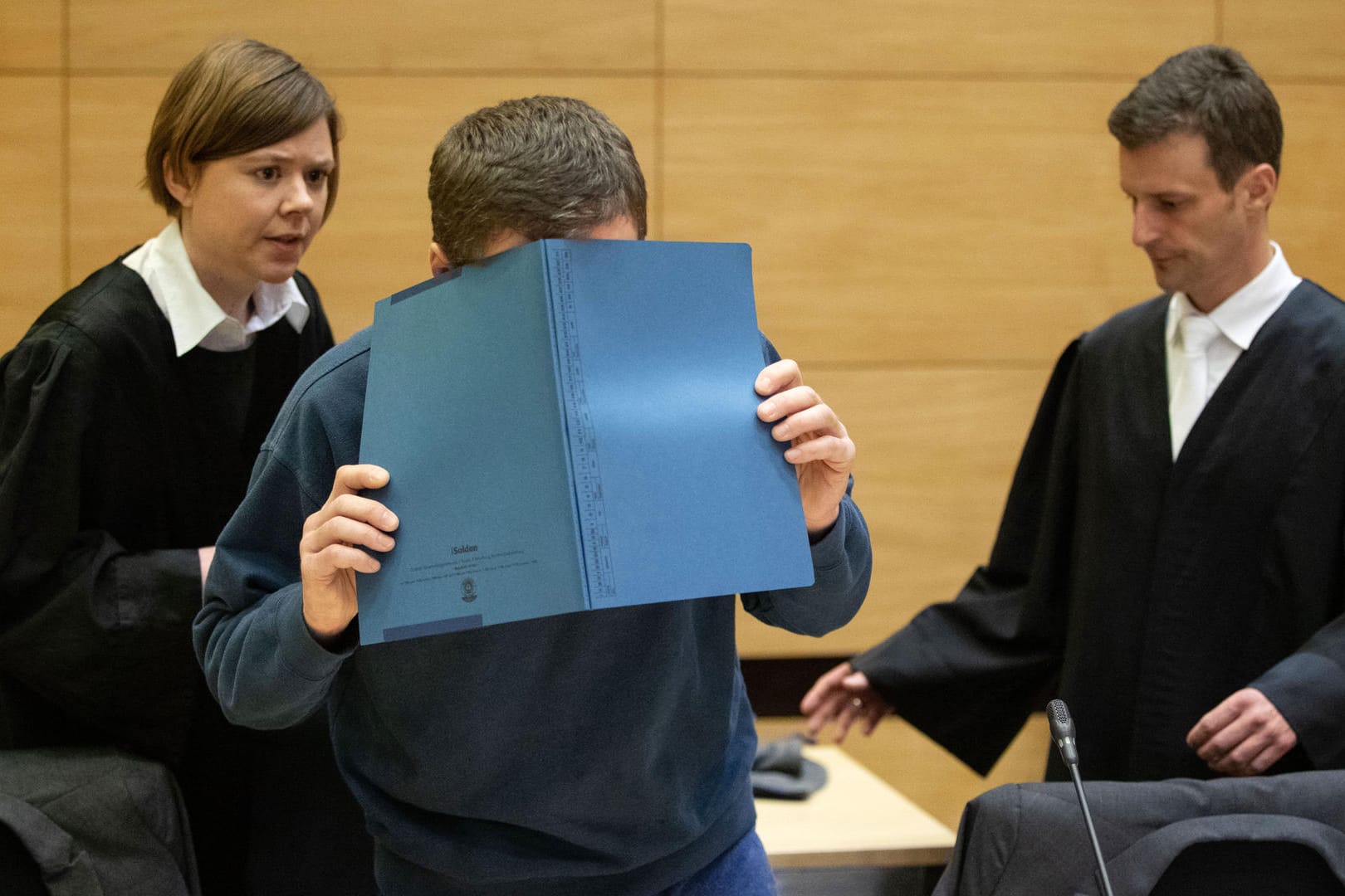 Die eigenen Kollegen vergiftet: Der Angeklagte Klaus O. verdeckt im Gerichtssaal in Bielefeld sein Gesicht mit einer Aktenmappe.