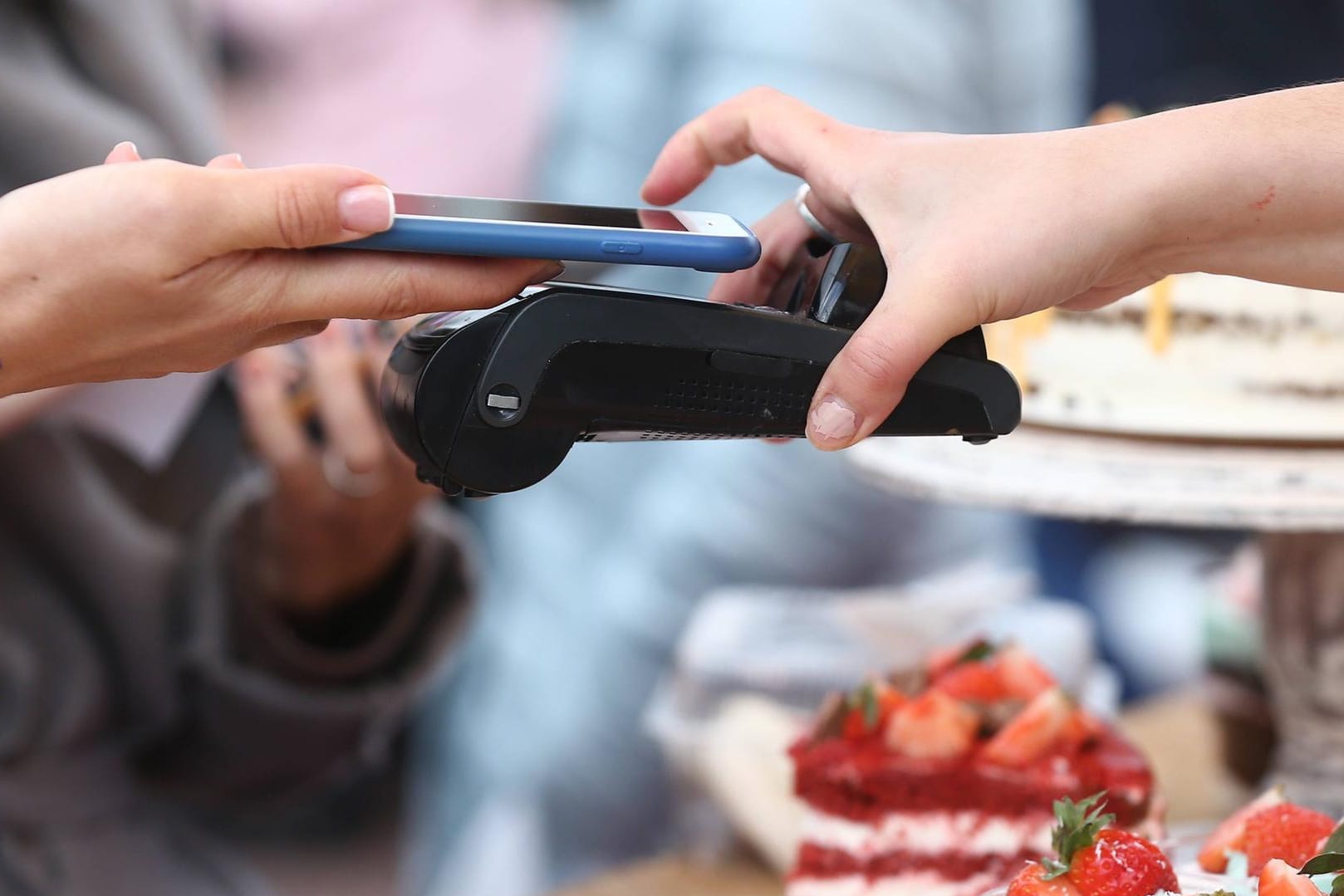 Ein Kunde zahlt in einer Konditorei mit dem iPhone: Die Sparkassen wollen ihren Kunden bald Apple Pay anbieten.