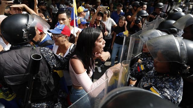 Eine Frau konfrontiert venezolanische Polizisten, die Teilnehmer einer Demonstration gegen die sozialistische Regierung von Präsident Maduro blockieren. Eine Frau konfrontiert venezolanische Polizisten, die Teilnehmer einer Demonstration gegen die sozialistische Regierung von Präsident Maduro blockieren.