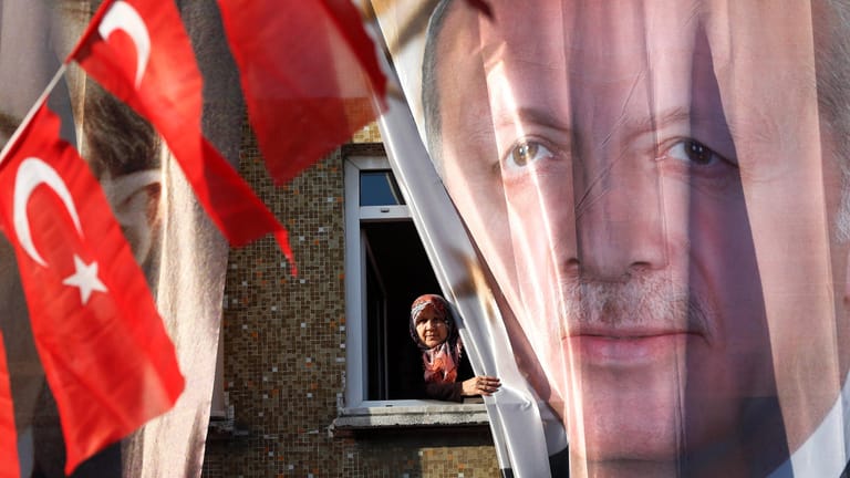 Eine Frau blickt aus ihrem Fenster hinter einem Banner des türkischen Präsidenten Erdogan: Das Auswärtige Amt hat die Reisehinweise für die Türkei verschärft.