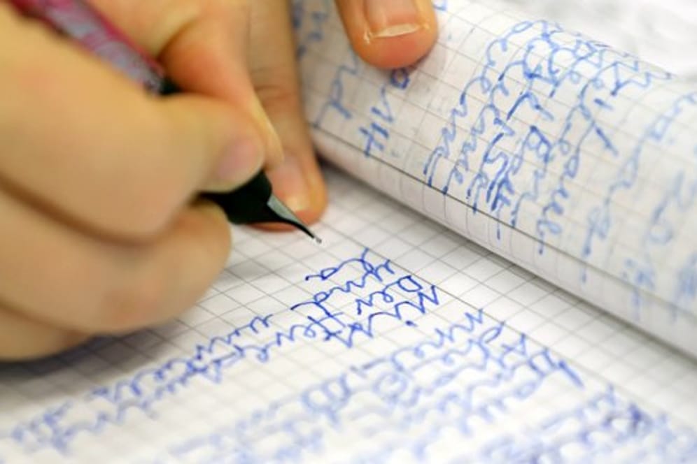 Eine Frau schreibt in der Volkshochschule Rostock bei einem Analphabeten-Grundkurs.