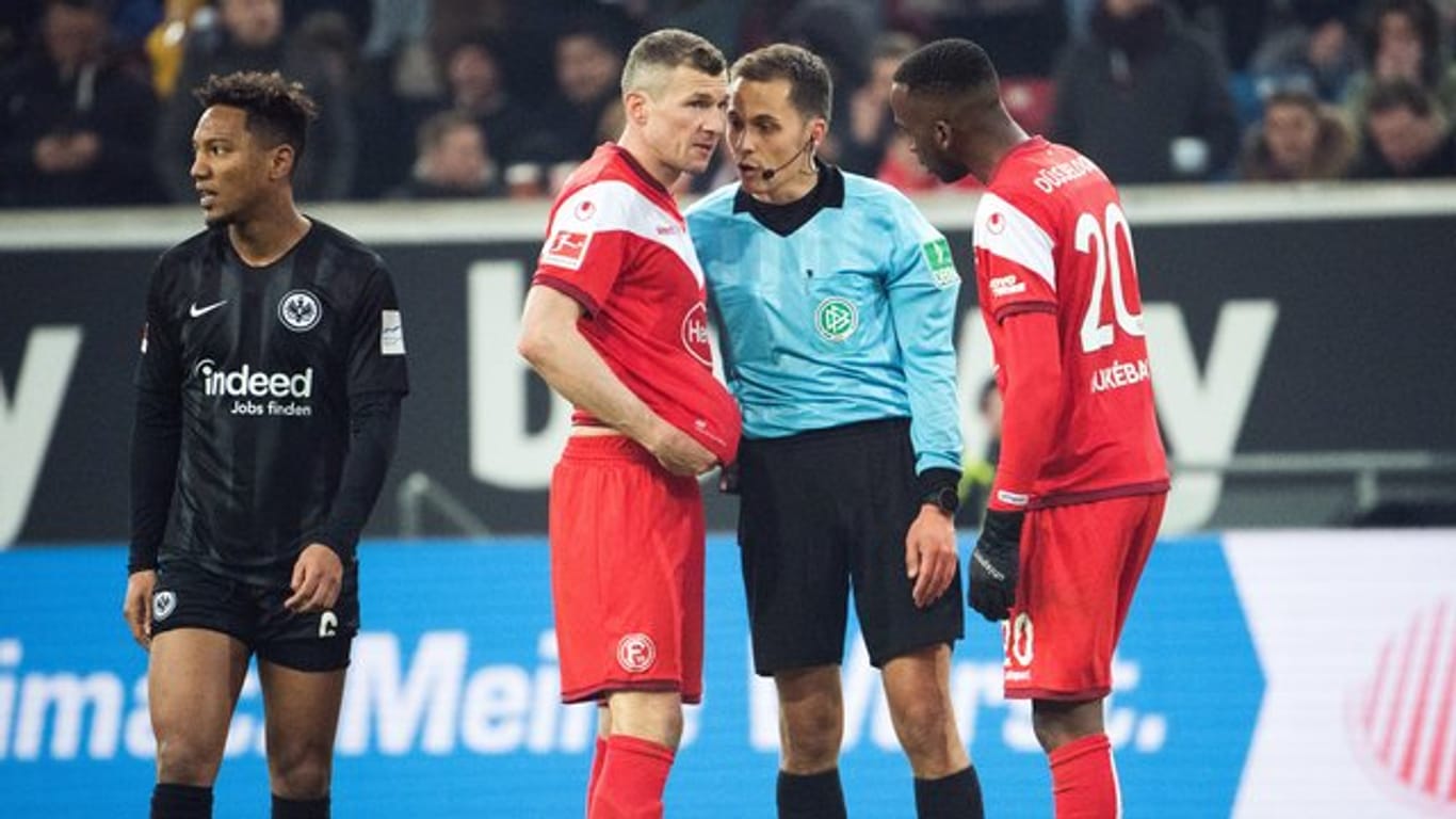 Schiedsrichter Robert Hartmann (M) erklärt Düsseldorfs Oliver Fink (l) und Dodi Lukebakio (r) warum er einen Elfmeter nach einem Video-Beweis zurückgenommen hat.