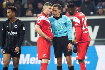 Schiedsrichter Robert Hartmann (M) erklärt Düsseldorfs Oliver Fink (l) und Dodi Lukebakio (r) warum er einen Elfmeter nach einem Video-Beweis zurückgenommen hat.