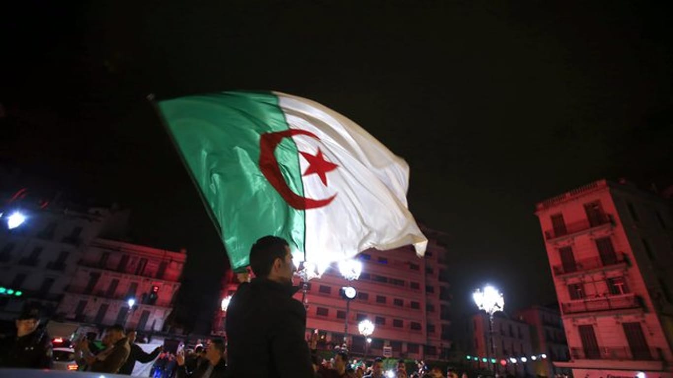 Ein Algerier schwenkt eine Nationalflagge, während Menschen feiern, nachdem Präsident Bouteflika angekündigt hat, dass er auf eine weitere Kandidatur verzichtet.