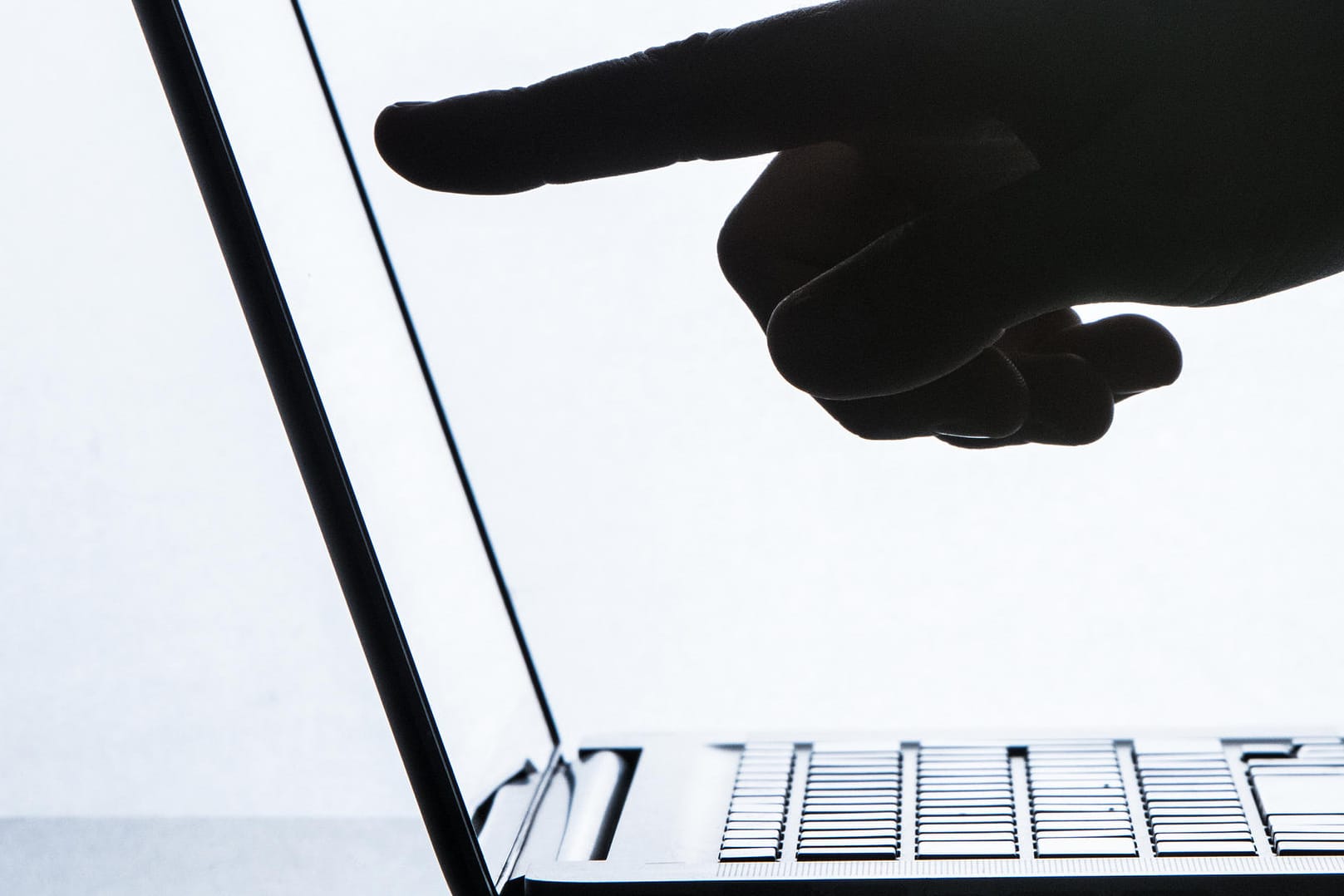 Finger deutet auf den Monitor eines Laptops