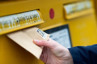 Ein Mann wirft einen Brief in einen Briefkasten (Symbolbild): Eine tote Maus in einem Brief löste einen Großeinsatz aus.