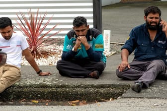 Geschockte Bürger sitzen nach einem Terrorangriff auf eine Moschee auf dem Gehweg.