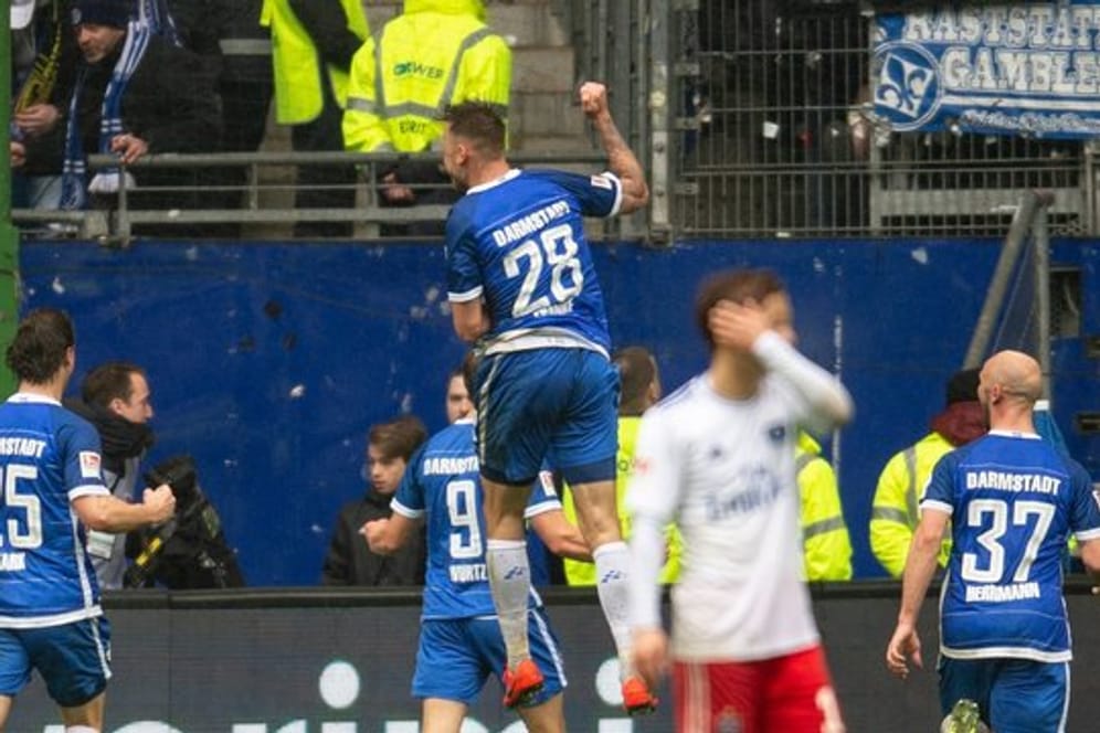 Während die Spieler von Darmstadt 98 den Treffer zum 3:2 in Hamburg feiern lässt ein HSV-Spieler den Kopf hängen.