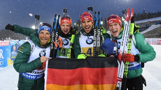 Erik Lesser (l-r-), Roman Rees, Arnd Peiffer und Benedikt Doll freuen sich mit einer deutschen Fahne über den zweiten Platz.