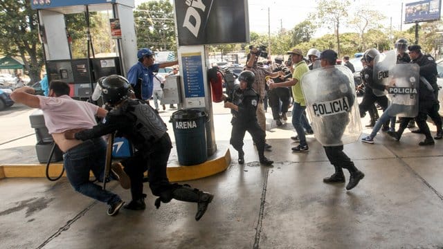 Polizisten gehen an einer Tankstelle in Managua gegen Demonstranten vor. Polizisten gehen an einer Tankstelle in Managua gegen Demonstranten vor.