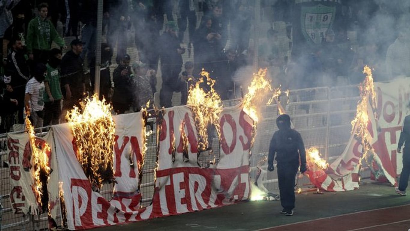 Vermummte Fans verbrennen während des Derbys ein Banner vor den Zuschauertribünen.