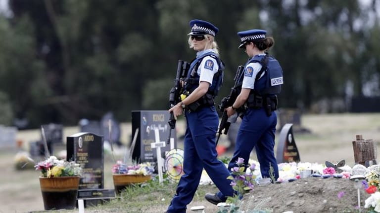 Bewaffnete Polizisten patrouillieren in der Nähe von muslimischen Gräbern auf einem Friedhof in Christchurch.