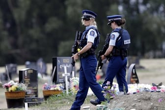 Bewaffnete Polizisten patrouillieren in der Nähe von muslimischen Gräbern auf einem Friedhof in Christchurch.