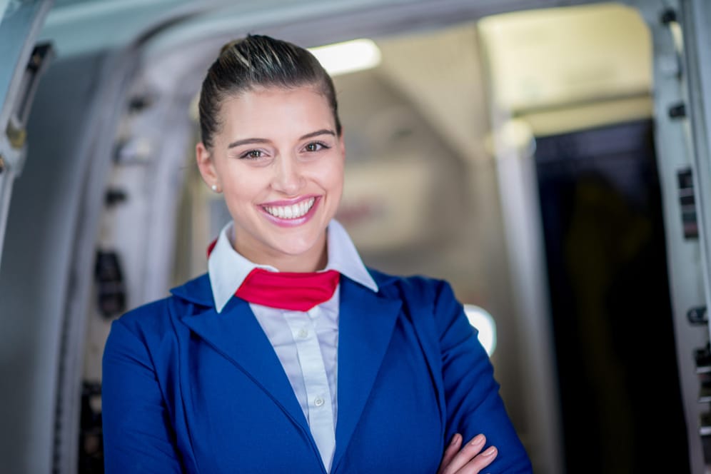 Stewardess am Eingang eines Flugzeugs: Das Flugpersonal darf selbst in Notsituationen sein Lächeln nicht verlieren.