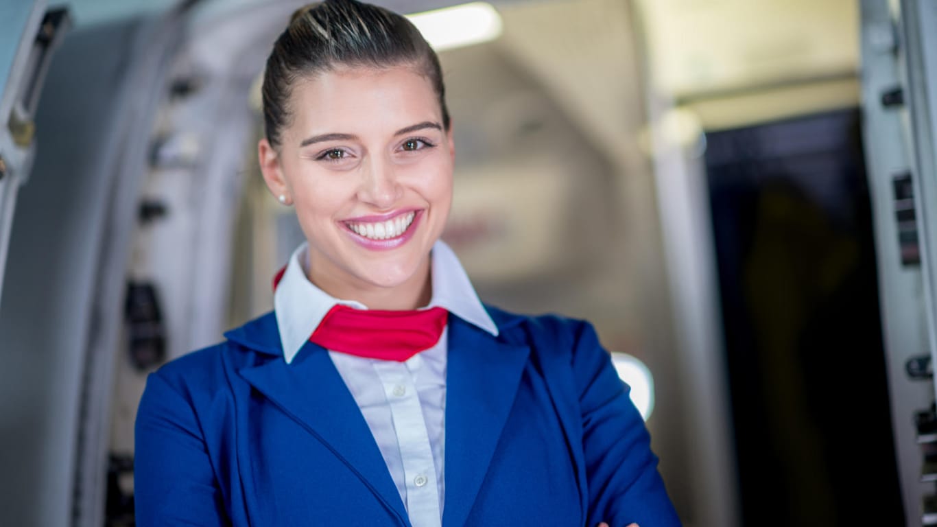 Stewardess am Eingang eines Flugzeugs: Das Flugpersonal darf selbst in Notsituationen sein Lächeln nicht verlieren.