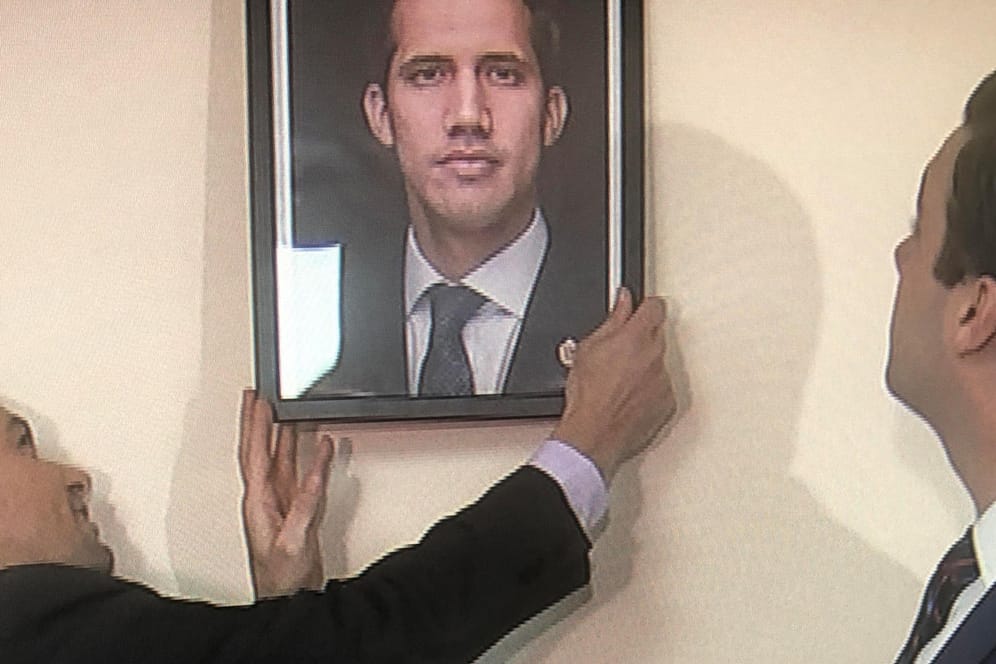 Der von Guaidó ernannte Botschafter in den USA, Carlos Vecchio, hängt ein Bild von Juan Guaidó in einem venezolanischen Konsulat auf: Der Machtkampf um die Führung in Venezuela geht erbittert weiter.