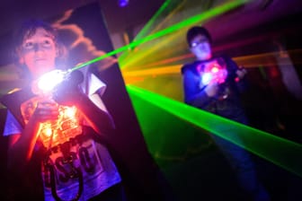 Ein Junge zielt mit einem "Phaser" auf andere Mitspieler: Beim Lasertag schießen die Mitspieler mit Laserpistolen aufeinander.