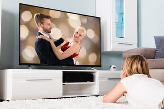Eine Frau schaut Fernsehen: Die Deutschen kaufen immer größere Fernseher.