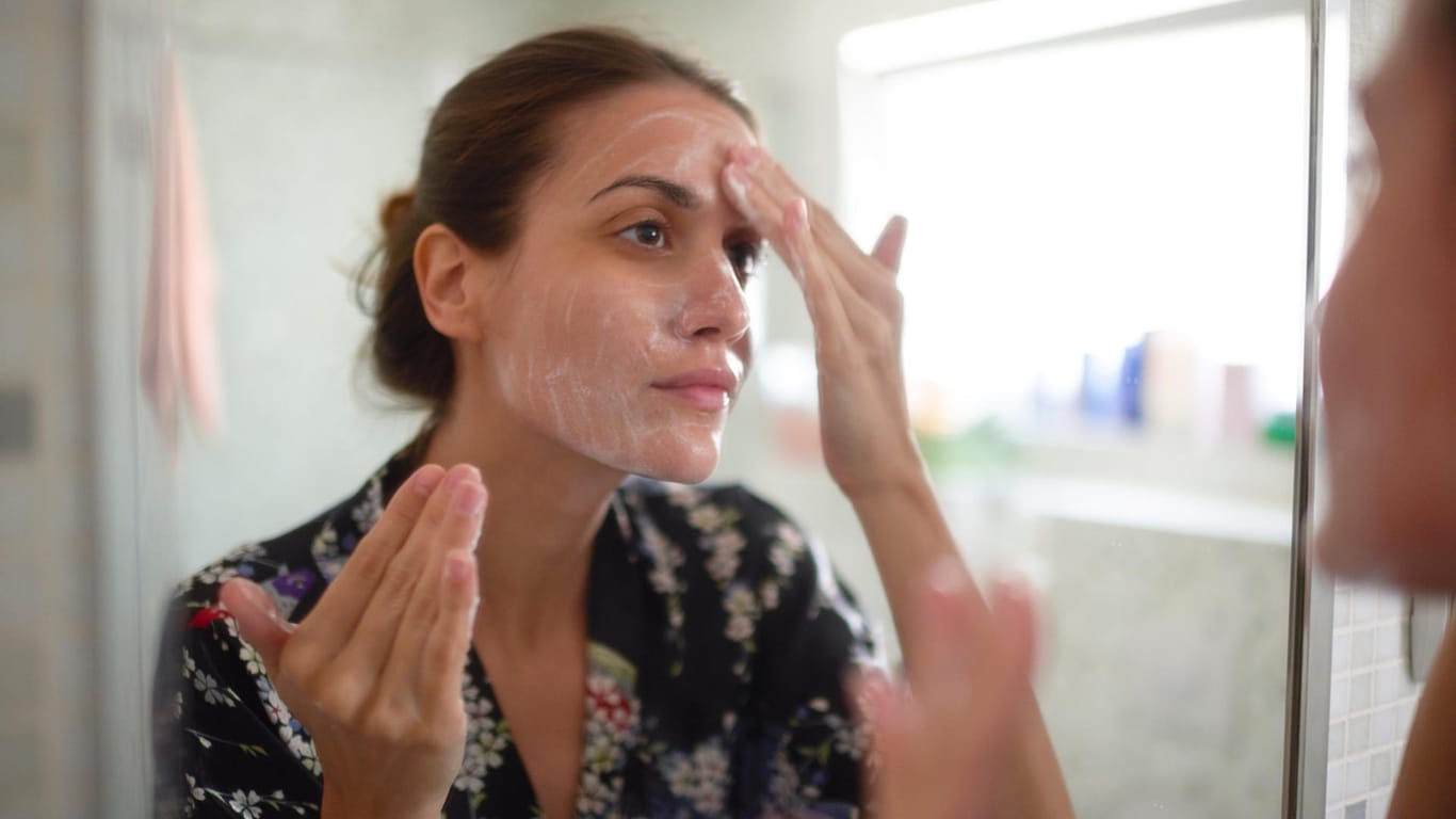 Frau cremt ihr Gesicht ein: Übermäßige Hautpflege kann Periorale Dermatitis verursachen.