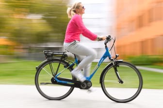 Frau auf einem Pedelec: Bevor es in den Straßenverkehr geht, sollte die Fahrdynamik des motorisierten Fahrrads auf einer hindernisfreien Fläche getestet werden.