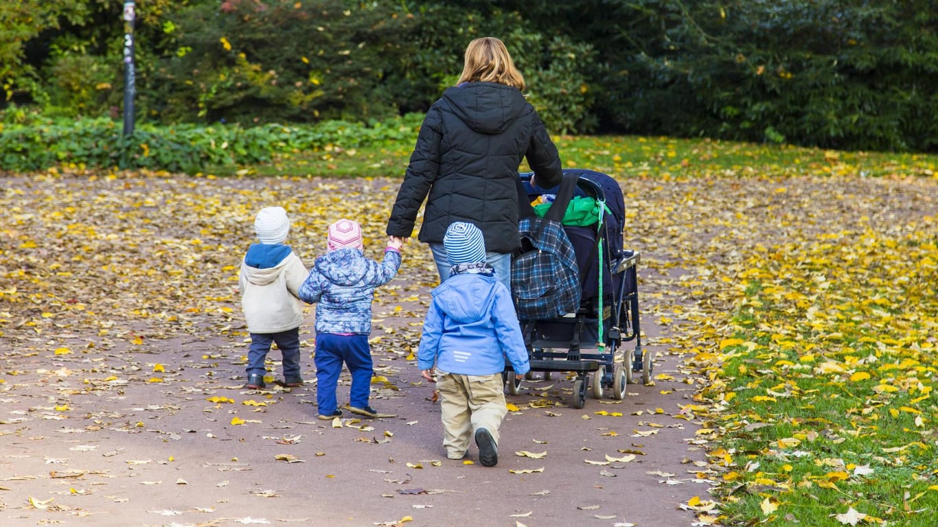 Mutter mit drei Kindern und Kinderwagen bei einem Spaziergang