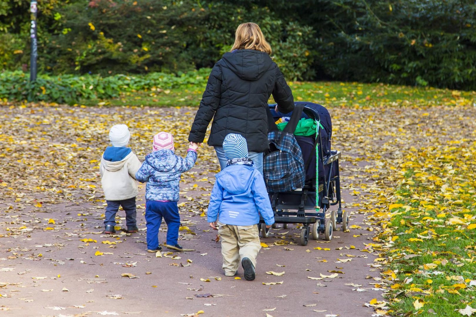 Mutter mit drei Kindern und Kinderwagen bei einem Spaziergang
