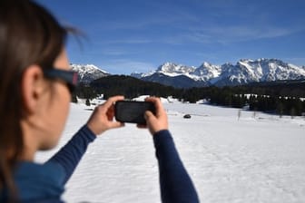 Fototourismus: Eine Frau fotografiert den mit Eis bedeckten Geroldsee vor dem Karwendel-Gebirge.