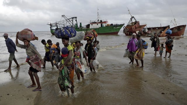 Familien kommen, nachdem sie 200 Kilometer vor Beira, aus einem überschwemmten Gebiet mit dem Boot gerettet wurden, am Strand an. Familien kommen, nachdem sie 200 Kilometer vor Beira, aus einem überschwemmten Gebiet mit dem Boot gerettet wurden, am Strand an.