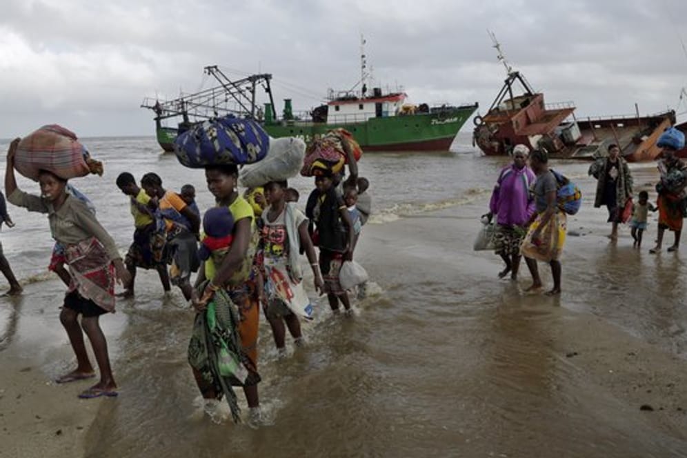 Familien kommen, nachdem sie 200 Kilometer vor Beira, aus einem überschwemmten Gebiet mit dem Boot gerettet wurden, am Strand an.