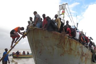 Ein Boot mit etwa 100 Menschen, die aus der überfluteten Region Buzi gerettet wurden, legt an einem Strand an.