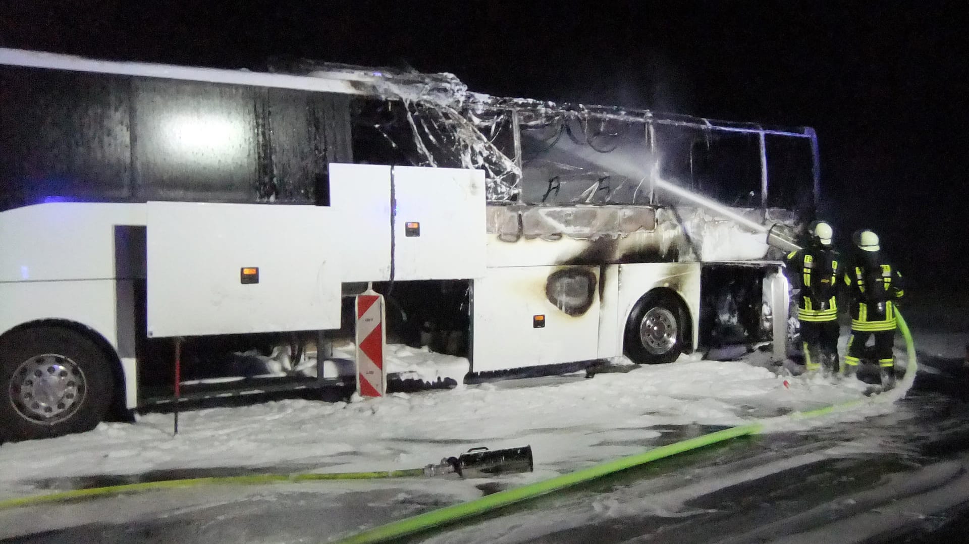 Feuerwehrleute stehen vor dem ausgebrannten Bus und löschen: Der Fahrer konnte sich in Sicherheit bringen, Fahrgäste waren nicht an Bord.