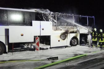 Feuerwehrleute stehen vor dem ausgebrannten Bus und löschen: Der Fahrer konnte sich in Sicherheit bringen, Fahrgäste waren nicht an Bord.