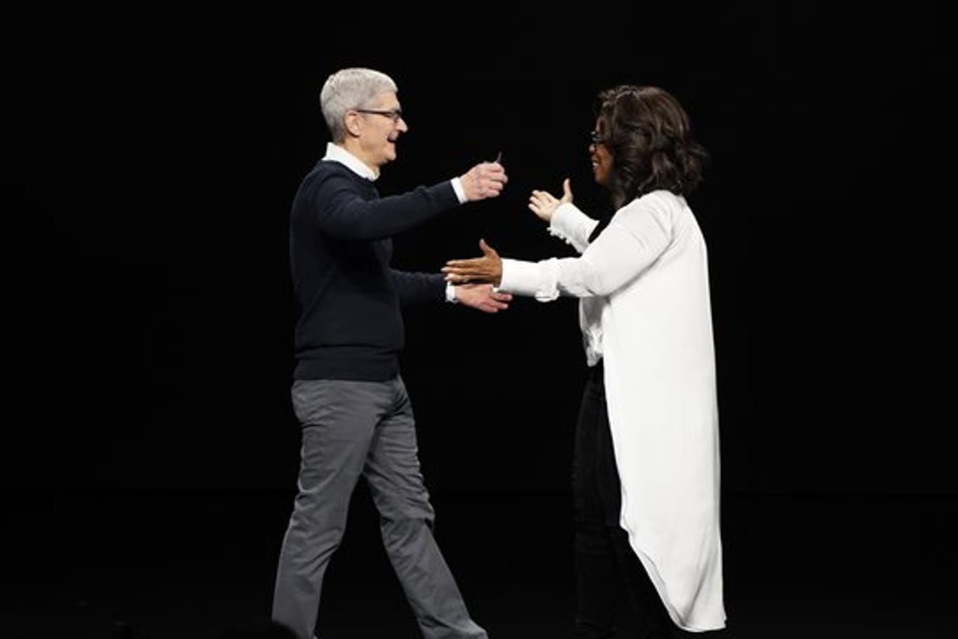 Tim Cook, Vorstandsvorsitzender von Apple, und Oprah Winfrey, Moderatorin aus den USA, begrüßen sich bei der Vorstellung neuer Apple-Produkte auf der Bühne.