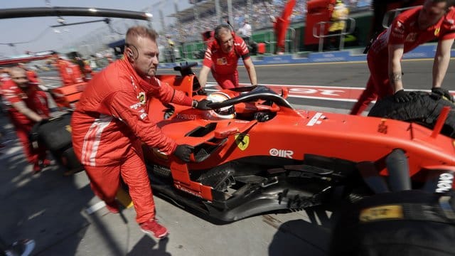 Die Boxencrew von Ferrari schiebt den Rennwagen von Sebastian Vettel in die Boxengasse. Die Boxencrew von Ferrari schiebt den Rennwagen von Sebastian Vettel in die Boxengasse.
