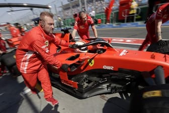 Die Boxencrew von Ferrari schiebt den Rennwagen von Sebastian Vettel in die Boxengasse.