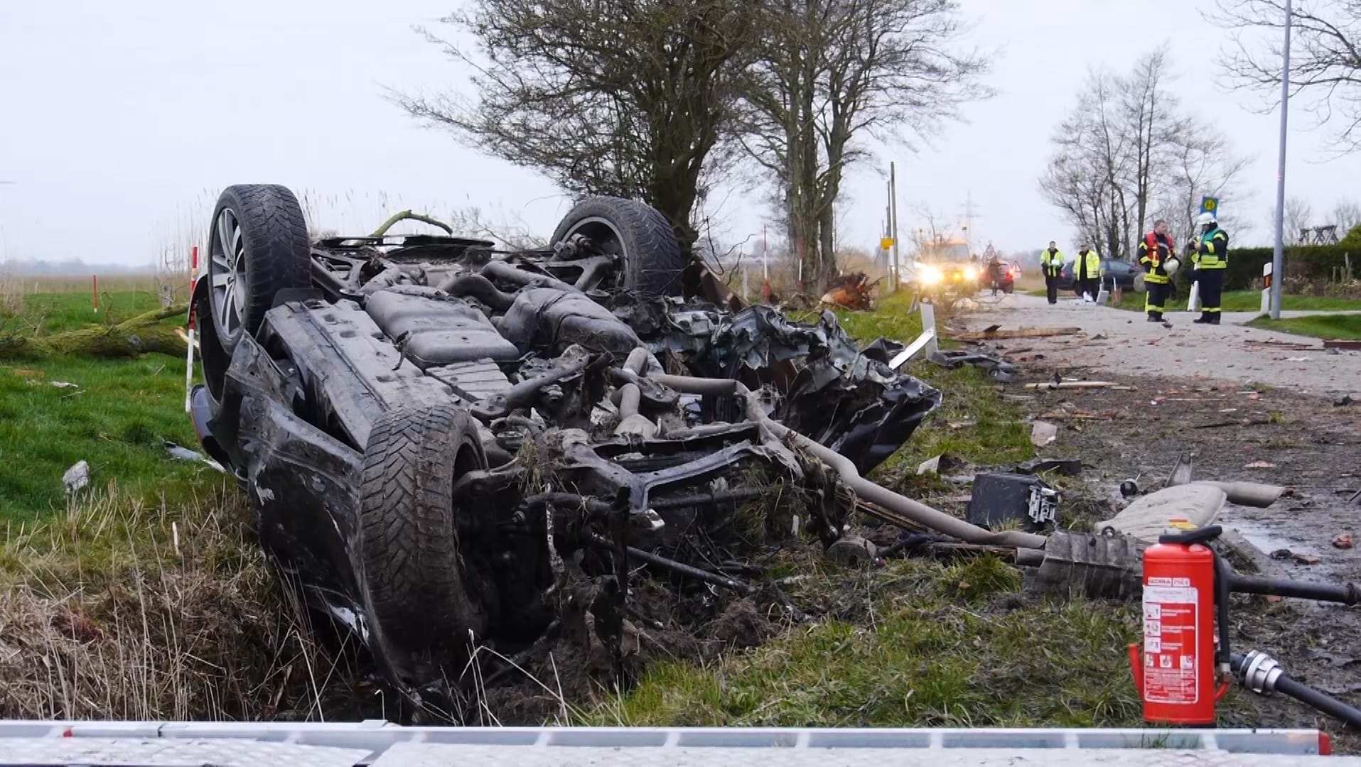 Ausgebrannt: Das Autowrack liegt nach dem Unfall im Landkreis Aurich am Straßenrand auf dem Dach.