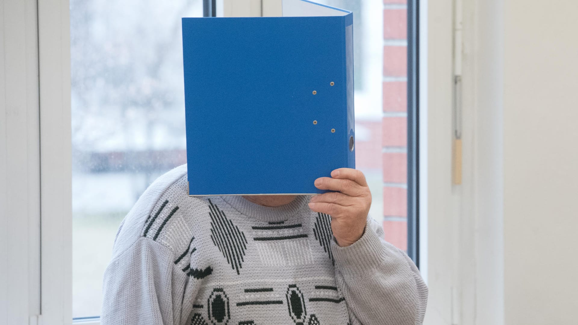 Stralsund: Der Angeklagte hält sich im Sitzungssaal einen Aktenordner vor das Gesicht. Stralsund: Der Angeklagte hält sich im Sitzungssaal einen Aktenordner vor das Gesicht.