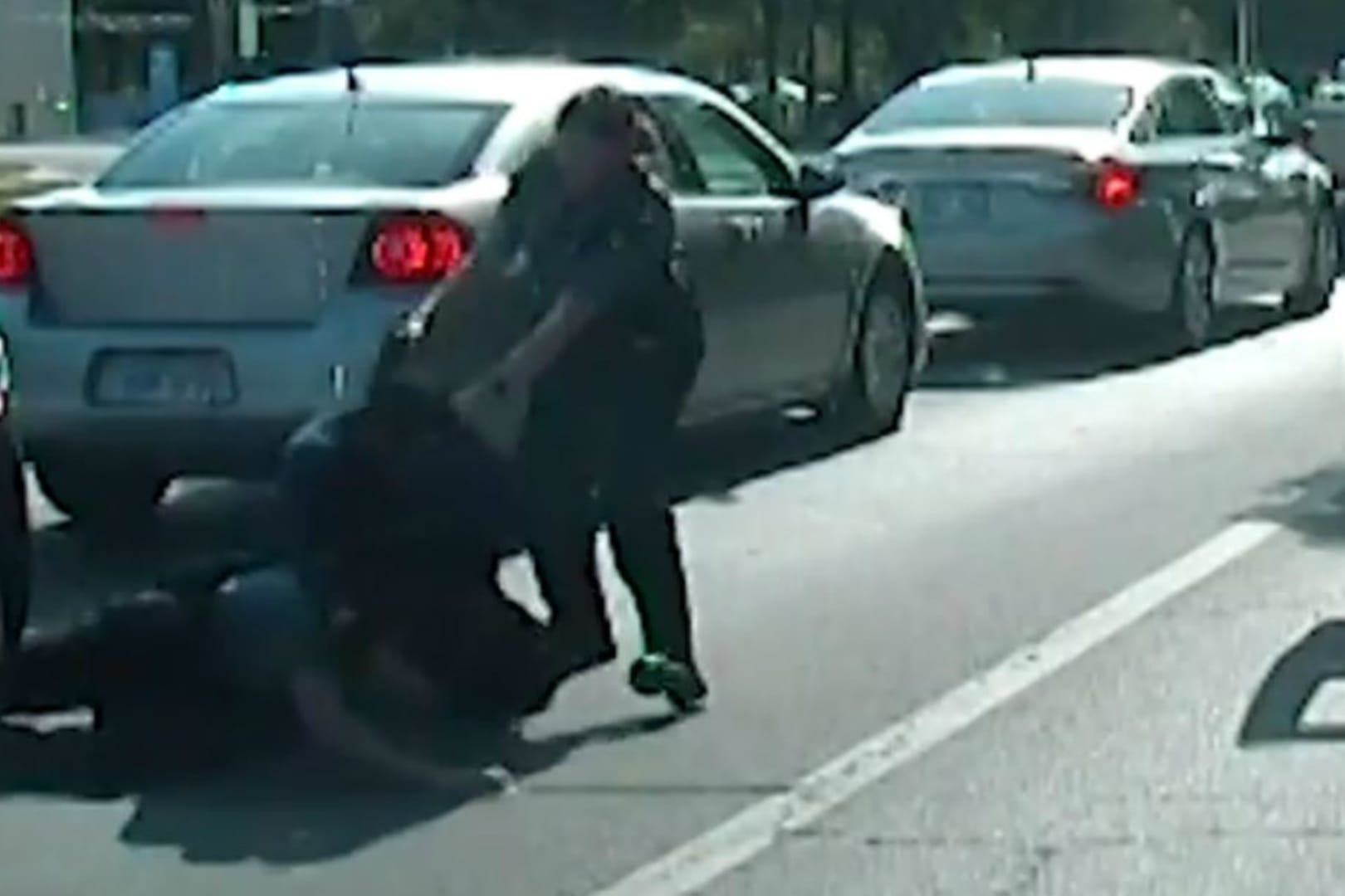 Screenshot aus dem Video der Polizei: Die Polizistin zielt mit einer Waffe auf die Schulterpartie des aggressiven Autofahrers.