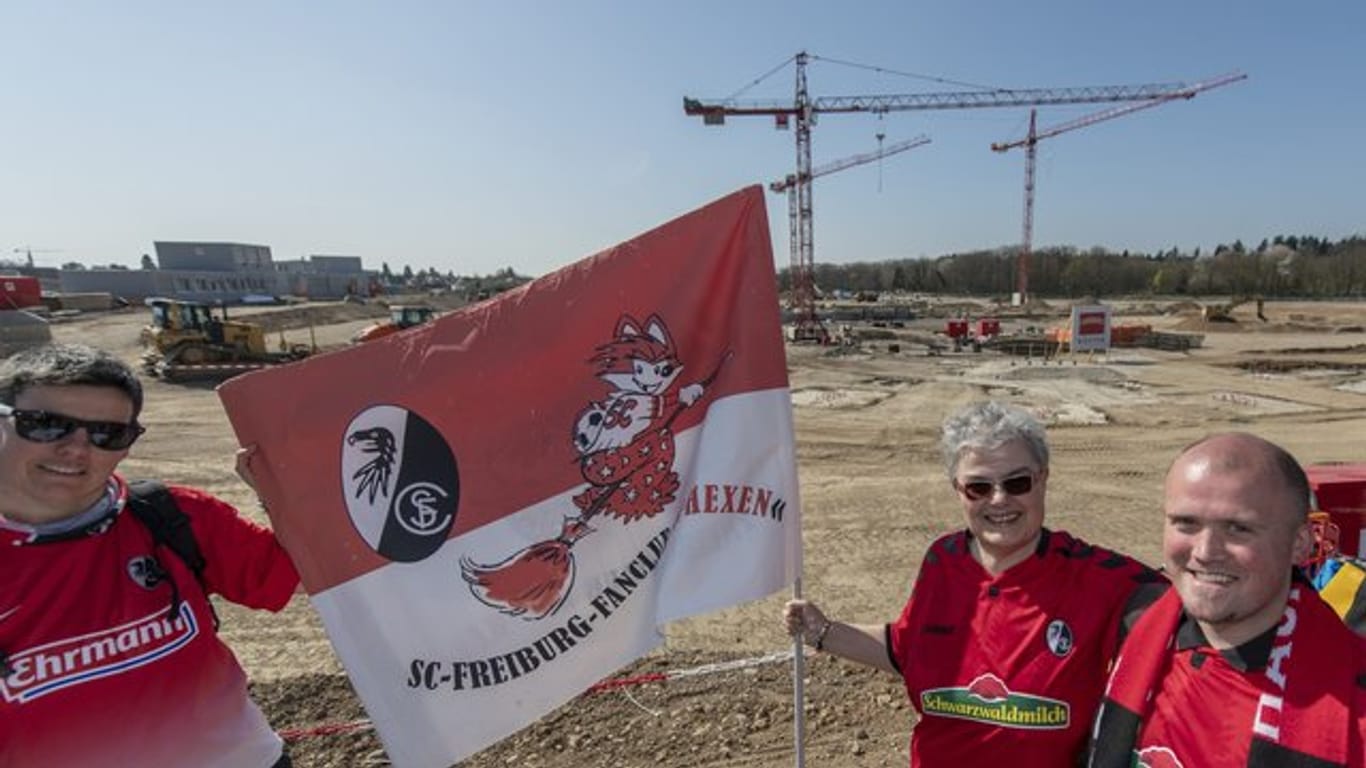 Fans stehen bei der Grundsteinlegung vor der Baustelle für das neue Stadion des SC Freiburg.
