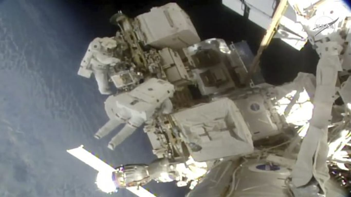 Die Astronauten Nick Hague und Christina Koch schweben an der Raumstation ISS im Weltall.