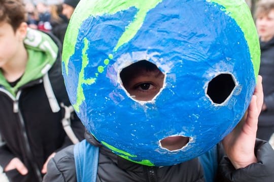 Bei einer "Fridays for Future"-Kundgebung hat sich ein Schüler mit einer Weltkugel aus Pappmache ausgestattet.