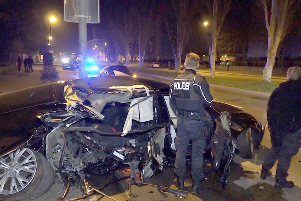 Polizisten stehen an einem völlig demolierten Auto in Magdeburg