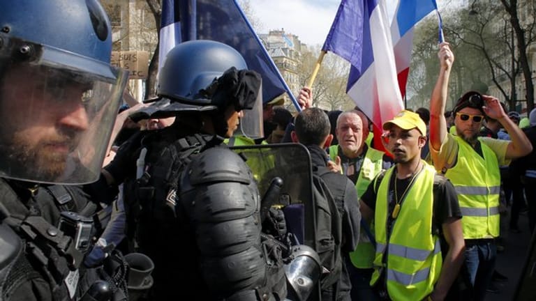 Polizisten vor Demonstranten und Anhängern der "Gelbwesten"-Bewegung, die an einer Protestkundgebung in Paris teilnehmen.