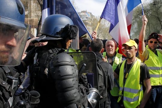 Polizisten vor Demonstranten und Anhängern der "Gelbwesten"-Bewegung, die an einer Protestkundgebung in Paris teilnehmen.