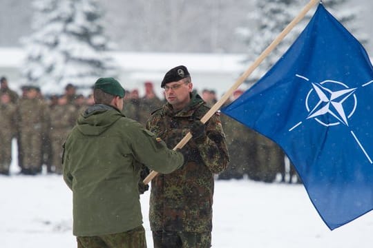 Der Brigadeführer von Iron Wolf, Steponauvicius Mindaugas, übergibt beim Übergabeappell die Natoflagge an Peter Papenbroock, Bundeswehr-Oberstleutnant und neuer Kommandeur der EFP Battlegroup in Litauen.