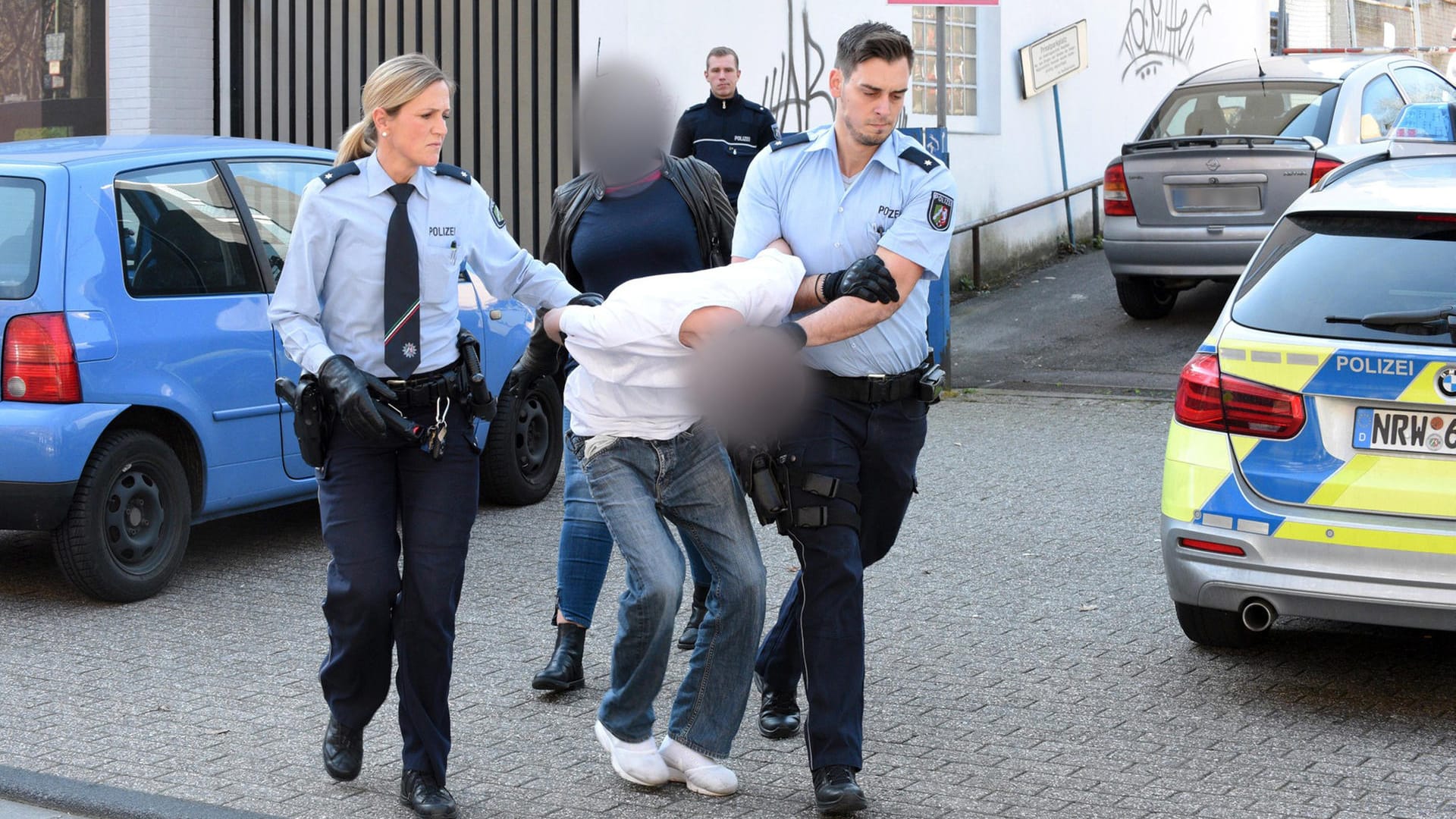 Der Verdächtige wird von Polizeibeamten abgeführt: Der 19-Jährige war angeblich aus Wut über eine Bankabsage am Freitag durch eine Fußgängerzone in Essen gefahren. Der Verdächtige wird von Polizeibeamten abgeführt: Der 19-Jährige war angeblich aus Wut über eine Bankabsage am Freitag durch eine Fußgängerzone in Essen gefahren.