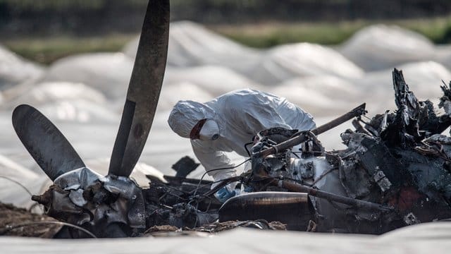 Ein Experte untersucht das ausgebrannte Flugzeugwrack.